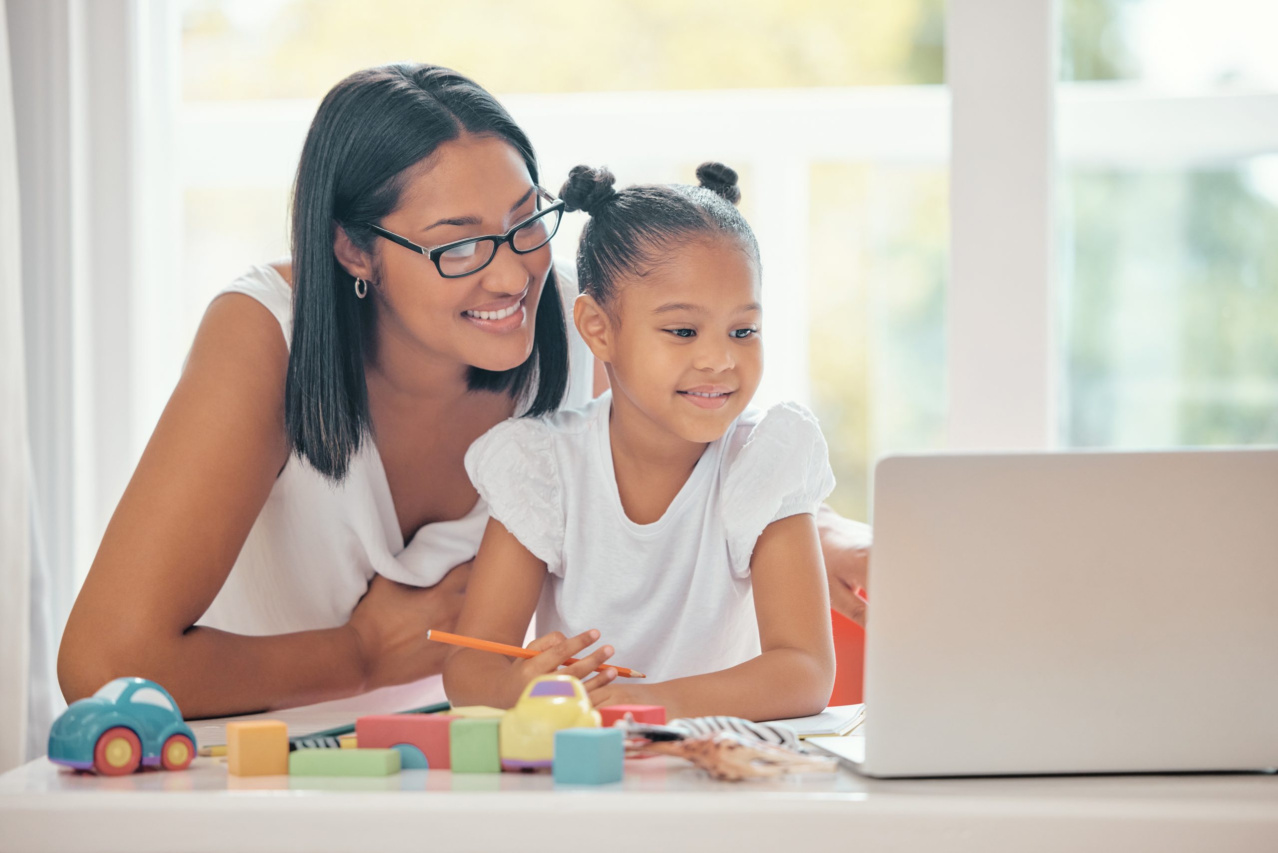 Mother helping her daughter with homework on a laptop.
