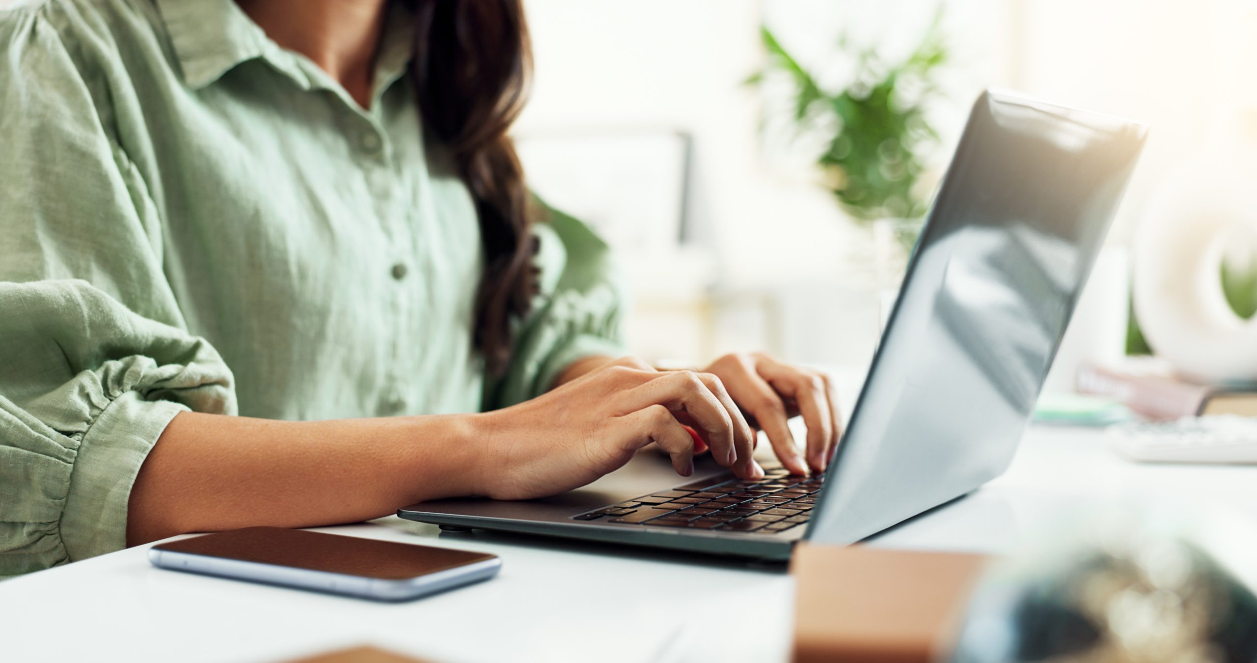 Woman typing on a computer in home office. 